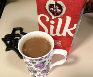 A cup of black tea next to a carton of Silk Original Soymilk