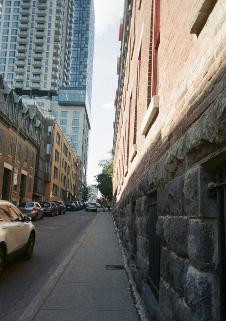 Narrow street with light reflecting off the building on the right.