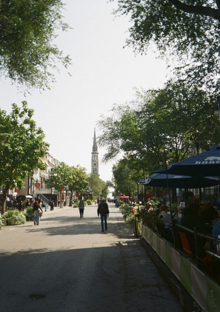 Looking down a street with a church spire in the distance.